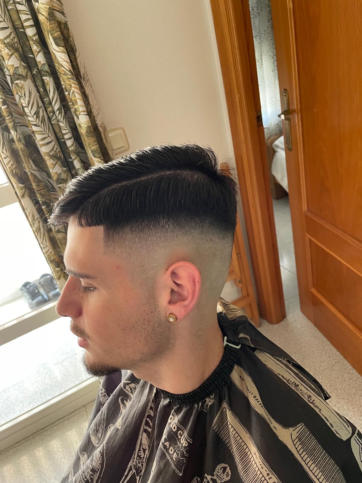Perfil de un chico con french crop: flequillo corto peinado hacia delante y degradado alto a piel en los laterales.
