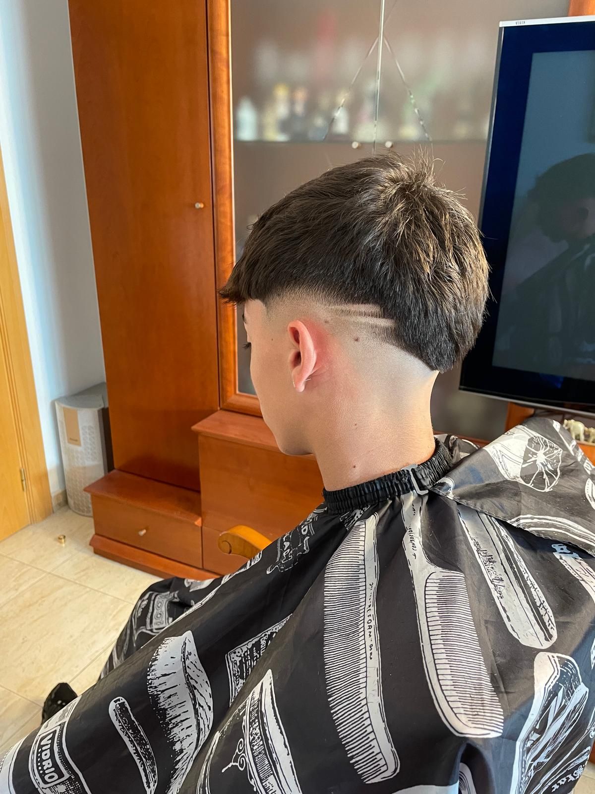 Vista trasera de un corte con degradado bajo, parte superior texturizada y una línea de diseño en el lateral.