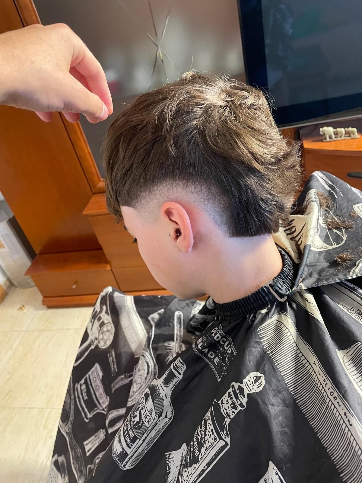 Mullet moderno con burst fade alrededor de la oreja y la parte trasera más larga.