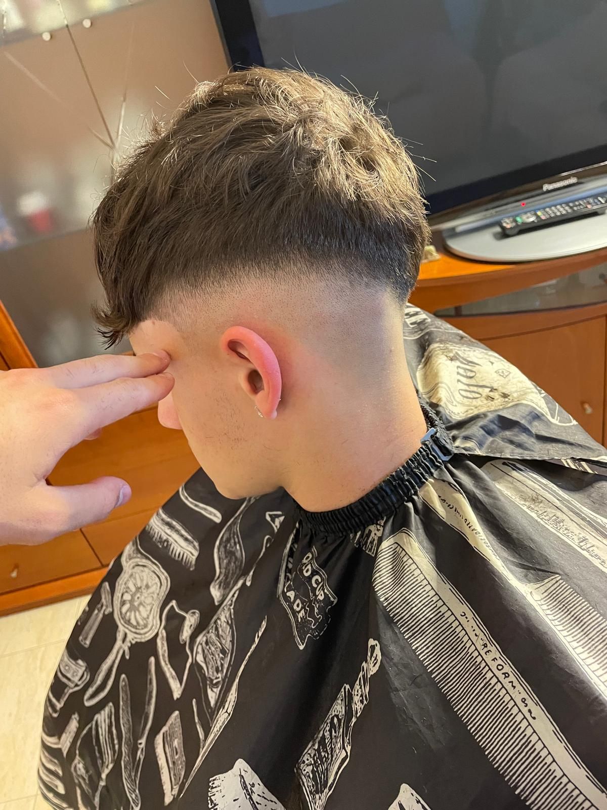 Corte texturizado con mid fade que baja por detrás de la oreja.